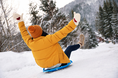 Photo of Woman sledding outdoors, back view. Winter vacation