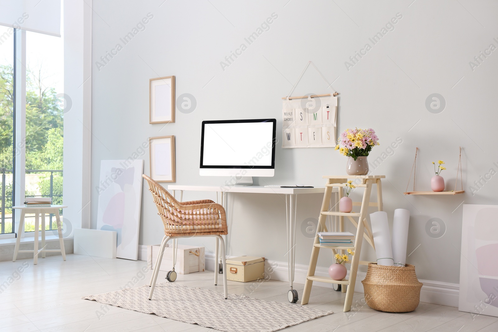 Photo of Comfortable workplace with modern computer and flowers in room. Interior design