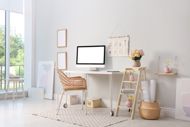 Comfortable workplace with modern computer and flowers in room. Interior design