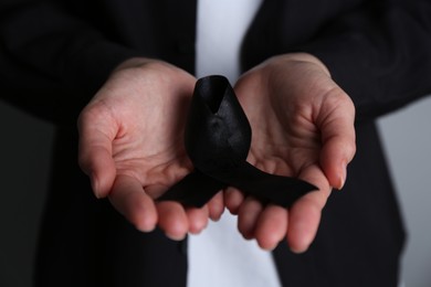 Photo of Woman holding black awareness ribbon, closeup view