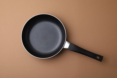Photo of One frying pan on light brown background, top view