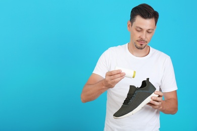 Photo of Man putting powder freshener into shoe on color background