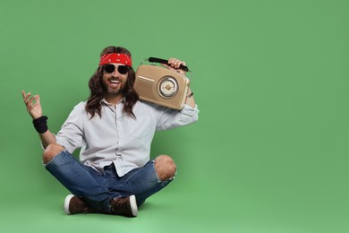 Stylish hippie man with retro radio receiver on green background, space for text