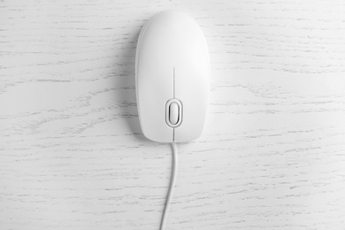Modern wired optical mouse on white wooden table, top view