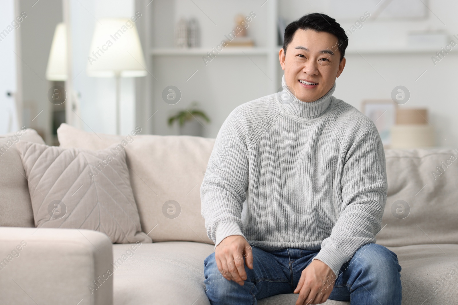 Photo of Portrait of smiling man on sofa indoors. Space for text