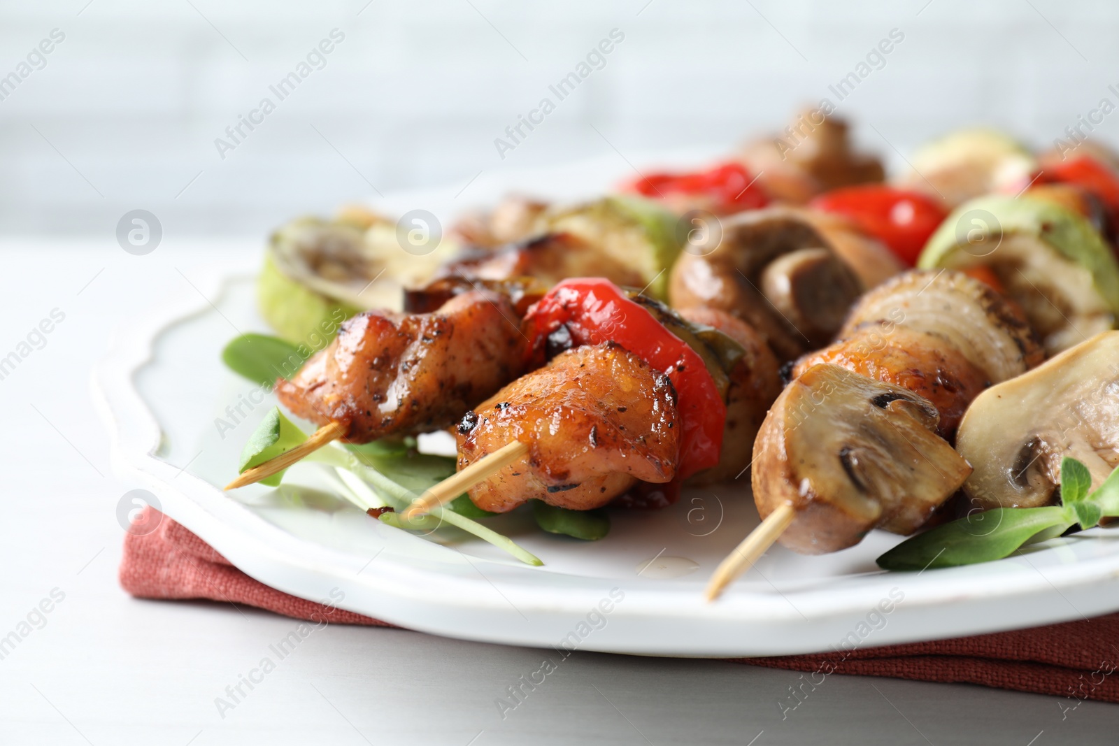 Photo of Delicious shish kebabs with vegetables and microgreens on white table, closeup