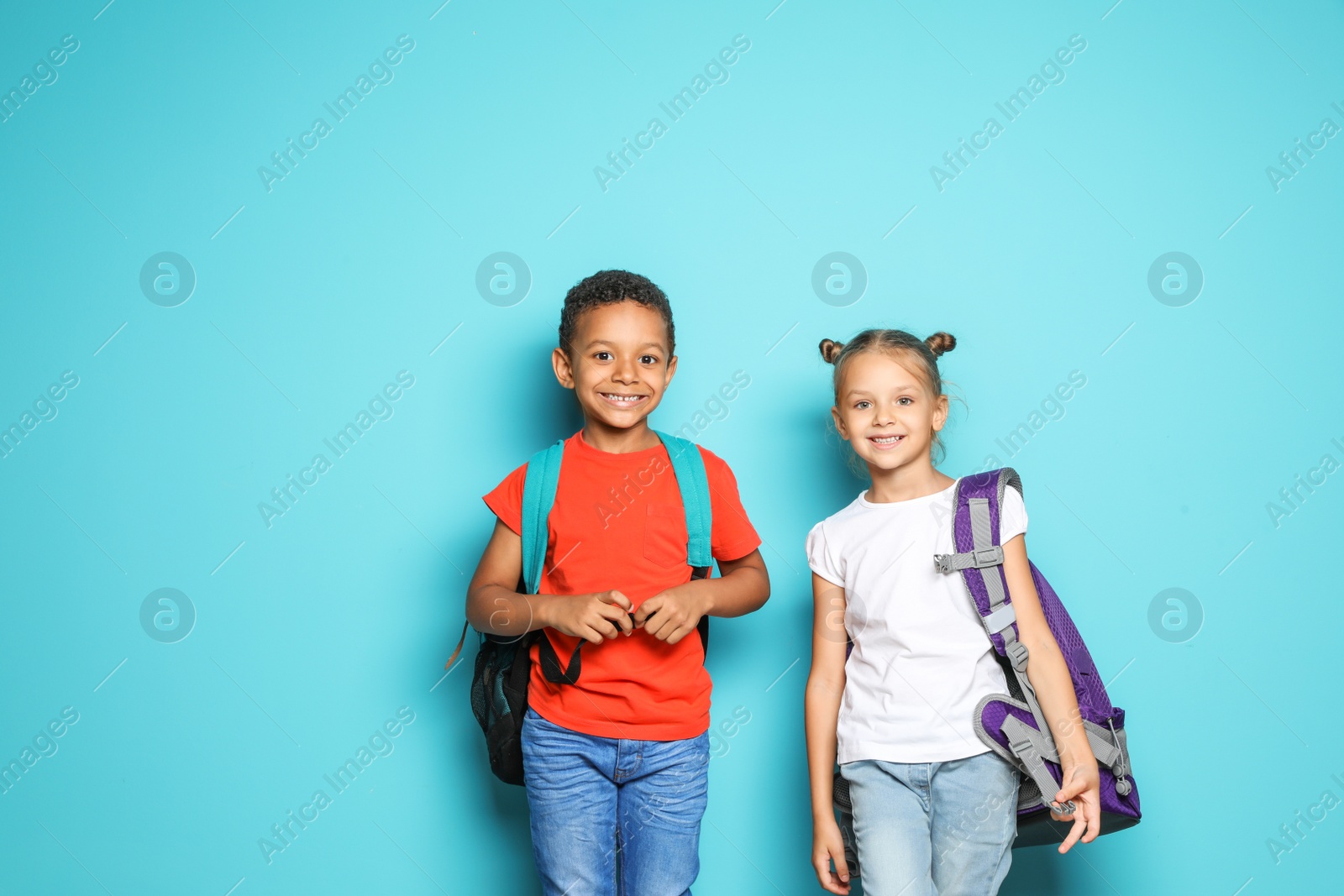 Photo of Little school children with backpacks on color background
