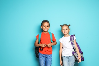 Photo of Little school children with backpacks on color background