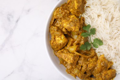 Photo of Delicious chicken curry with rice on white marble table, top view. Space for text