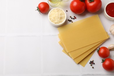 Ingredients for lasagna on white tiled table, flat lay. Space for text