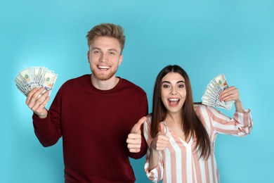 Photo of Young couple with money on color background