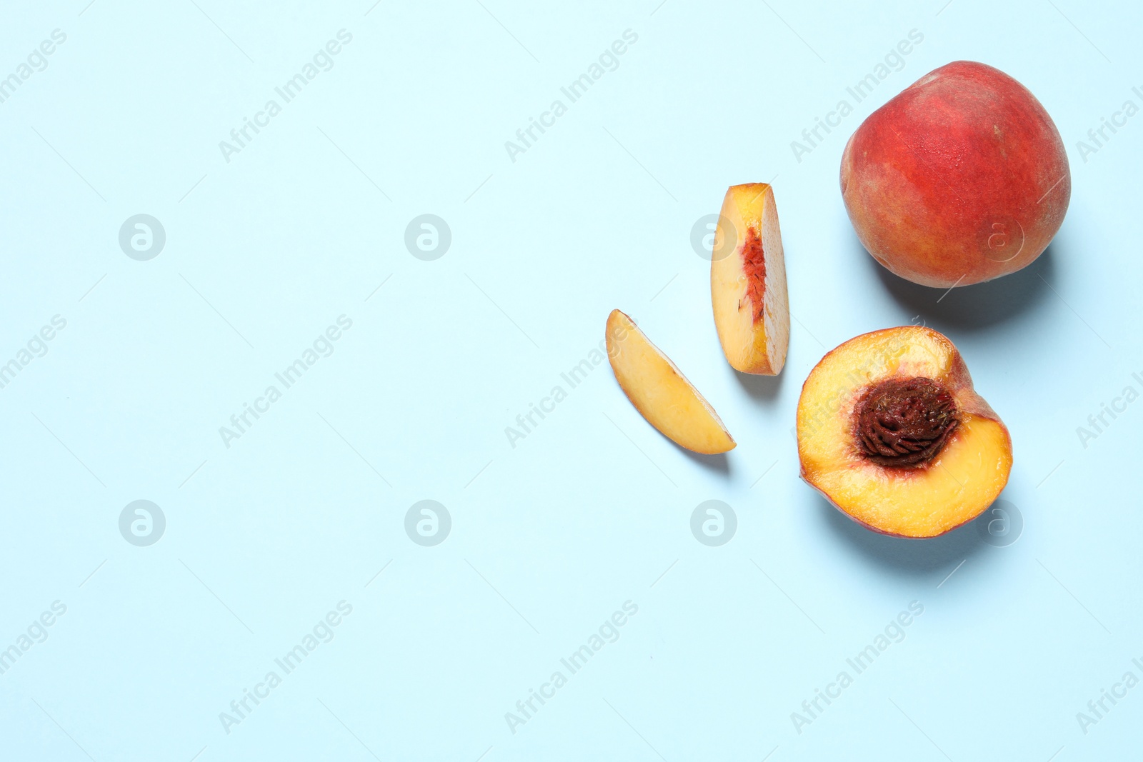 Photo of Delicious juicy peaches on light blue background, flat lay. Space for text