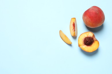 Photo of Delicious juicy peaches on light blue background, flat lay. Space for text