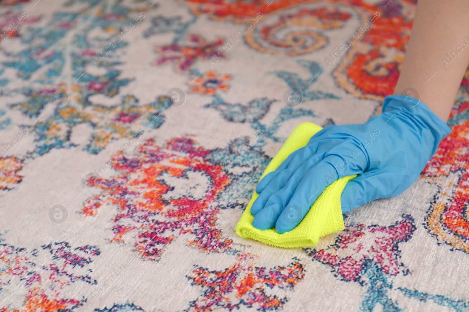 Photo of Woman in rubber gloves cleaning carpet with rag, closeup. Space for text