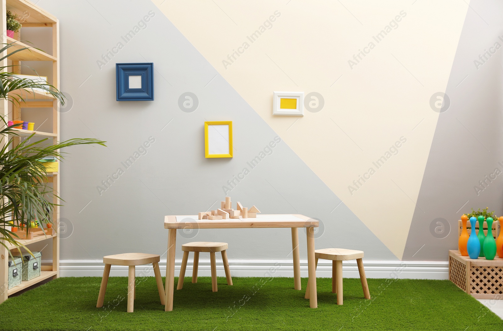 Photo of Stylish playroom interior with table, stools and green carpet