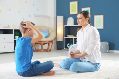 Female psychologist working with cute little boy in office