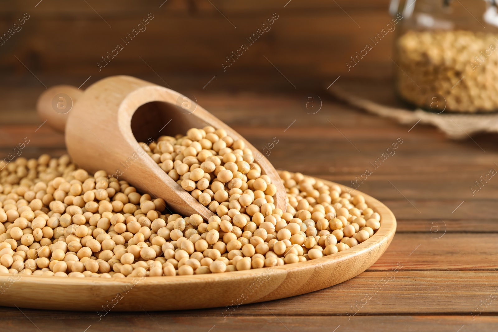 Photo of Plate with soy and scoop on wooden table, closeup