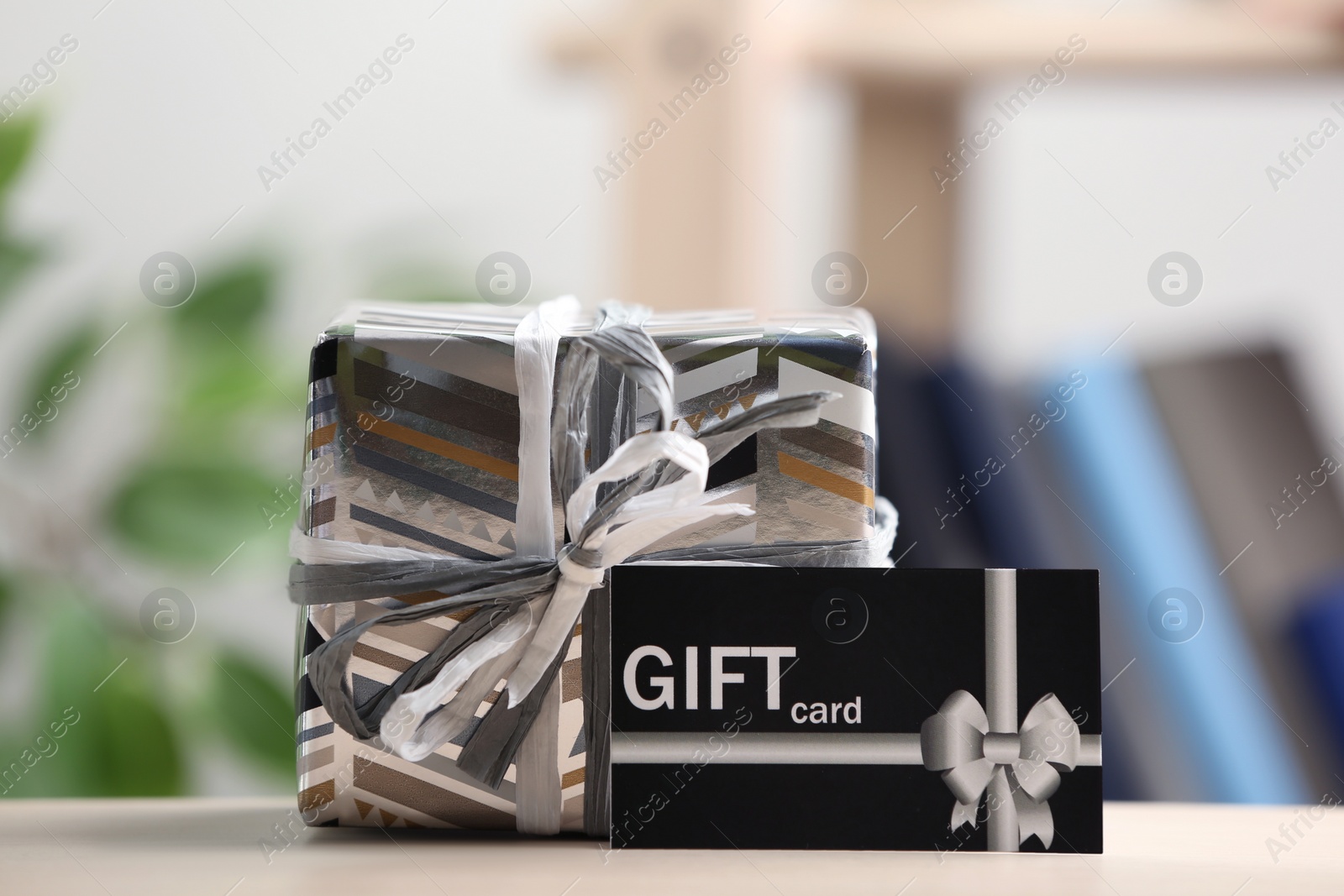 Photo of Gift card and present on table against blurred background