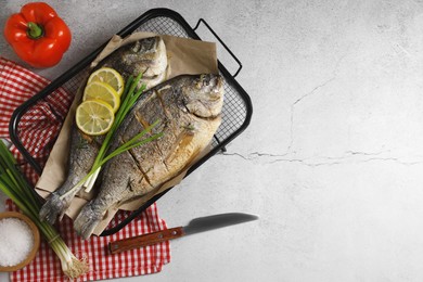 Seafood. Delicious baked fish served with green onion and lemon on light textured table, flat lay with space for text