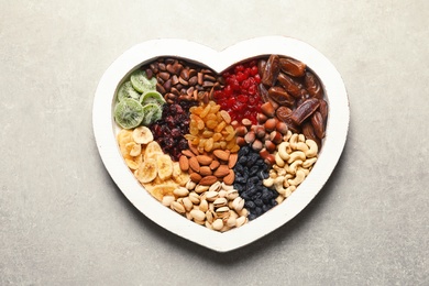 Photo of Heart shaped plate with different dried fruits and nuts on table