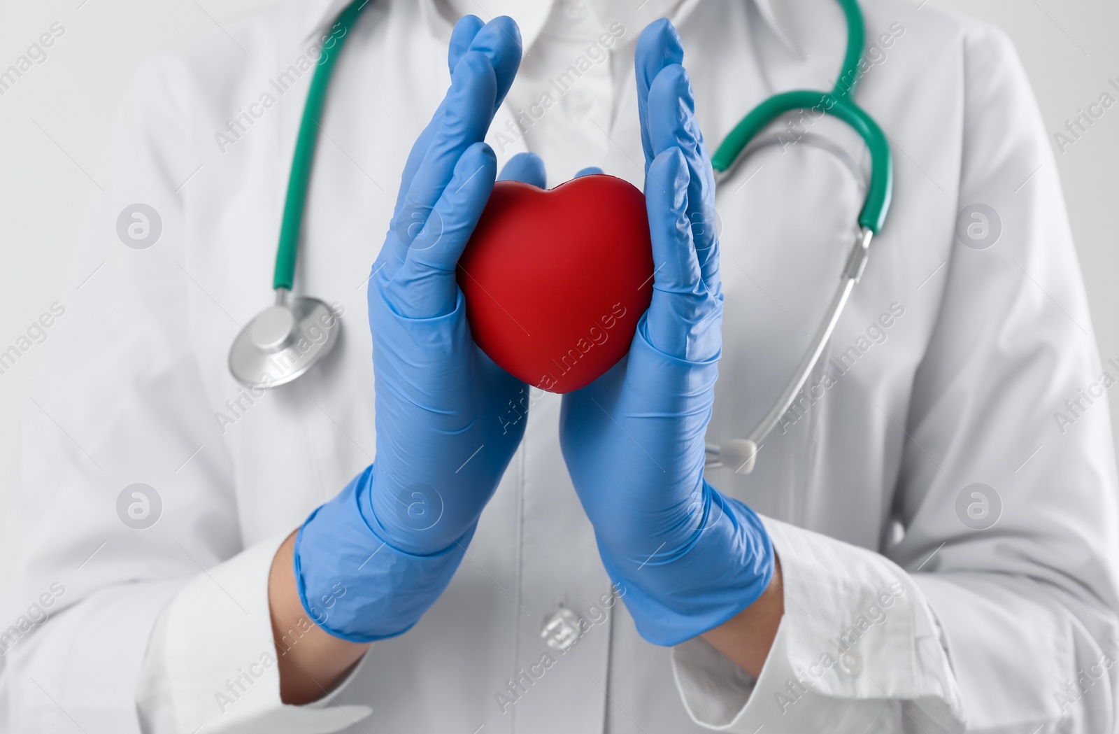 Photo of Doctor with stethoscope and red heart on white background, closeup. Cardiology concept