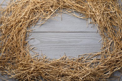 Photo of Frame of dried straw on grey wooden table, top view. Space for text