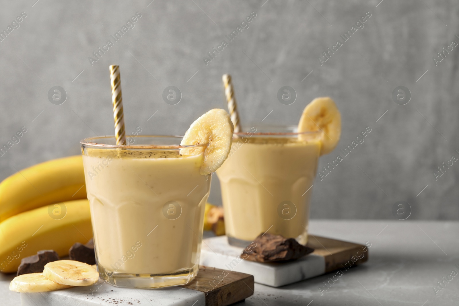 Photo of Tasty banana smoothie, fresh fruits and chocolate on white marble table