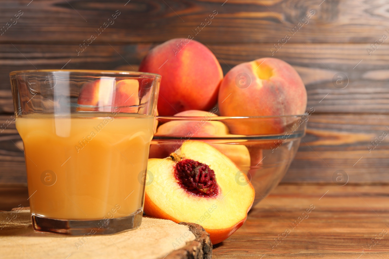 Photo of Glass of delicious peach juice and fresh fruits on wooden table, closeup. Space for text
