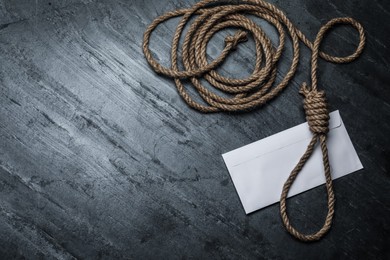 Rope noose and blank envelope on black table, flat lay. Space for text