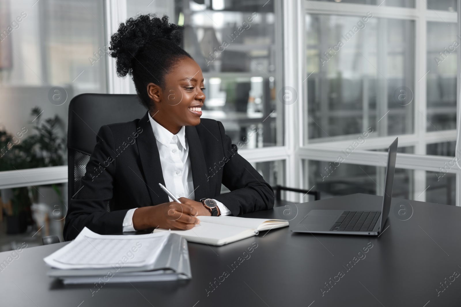 Photo of Happy woman working at table in office. Lawyer, businesswoman, accountant or manager