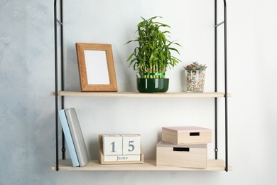 Photo of Shelves with green lucky bamboo in pot and decor on light wall