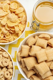 Photo of Different breakfast cereals and honey on white table, flat lay