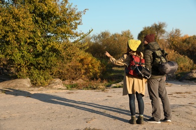 Photo of Couple of campers with backpacks and sleeping bags in wilderness. Space for text