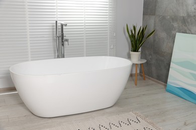Photo of Stylish bathroom interior with ceramic tub and houseplant