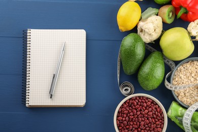 Photo of Healthy diet. Different products, notebook, measuring tape on blue wooden table, flat lay