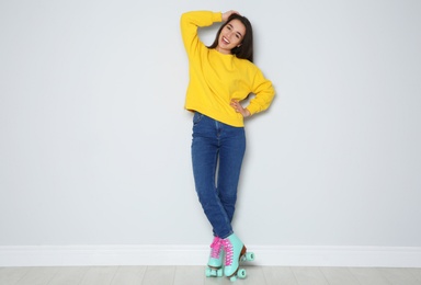 Full length portrait of young woman with roller skates near color wall