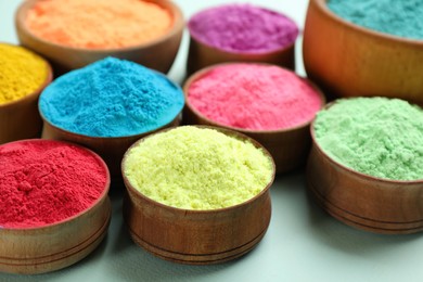 Photo of Colorful powders in wooden bowls on light background. Holi festival celebration