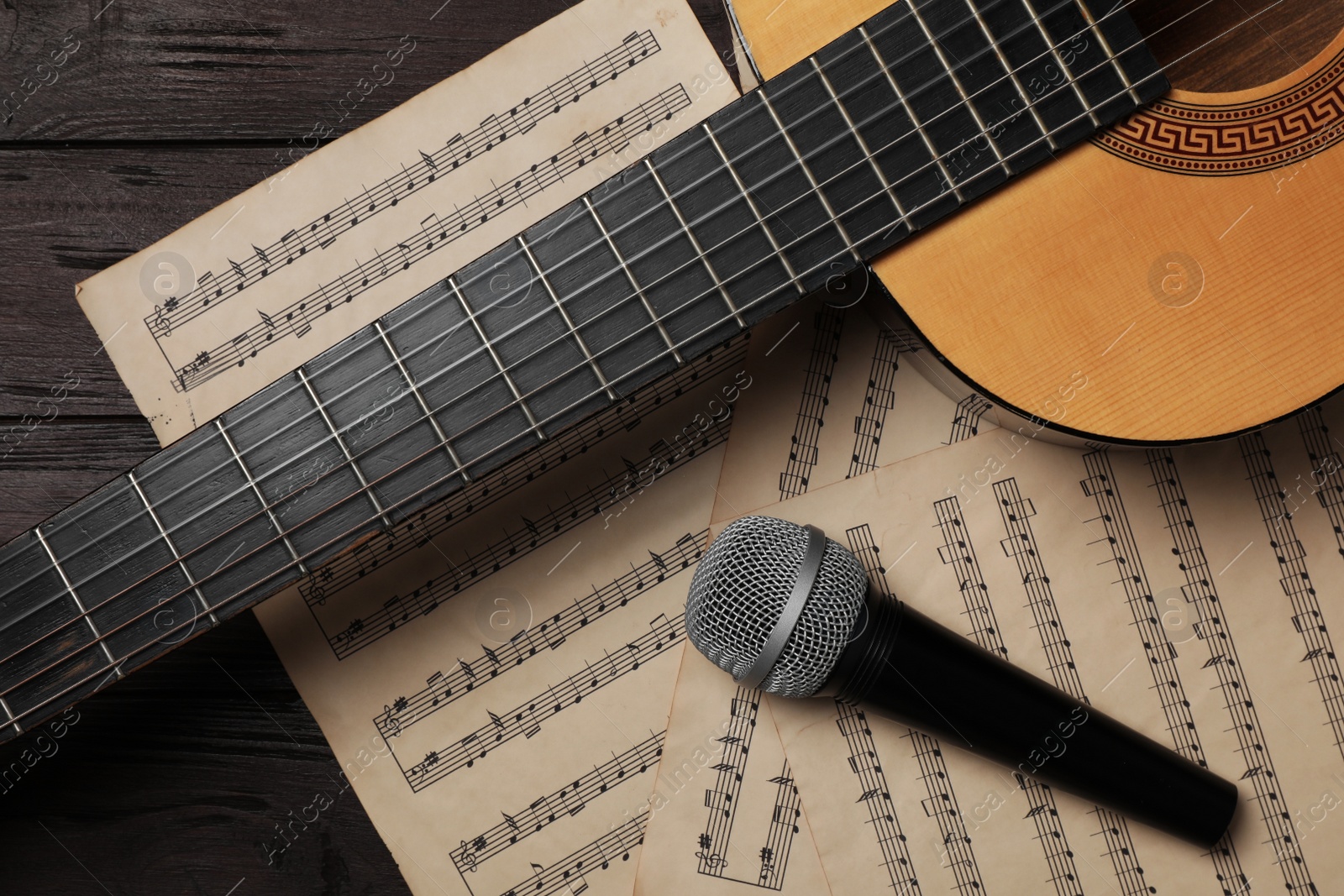 Photo of Composition with guitar and music notations on wooden table, flat lay