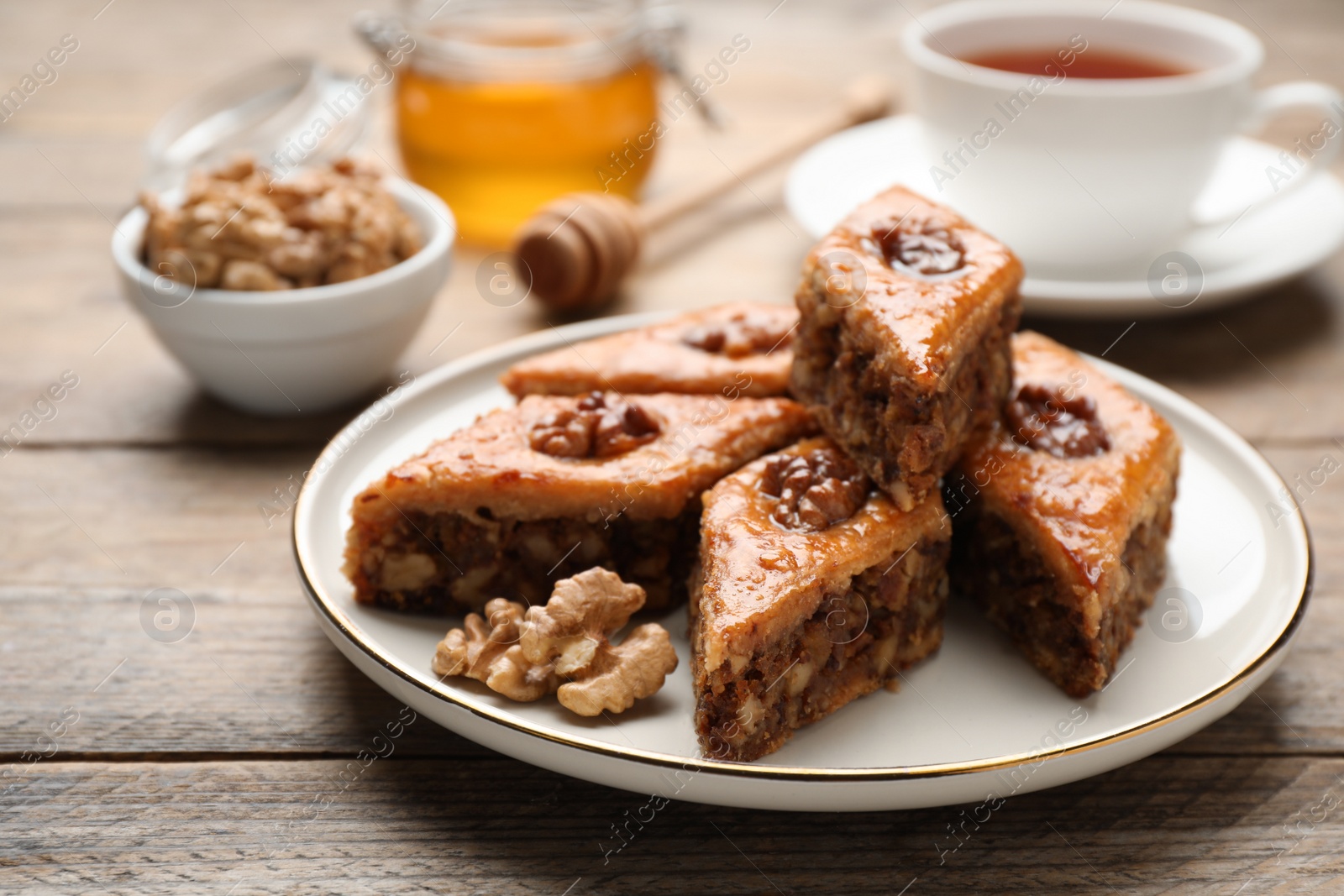 Photo of Delicious honey baklava with walnuts served on wooden table, closeup