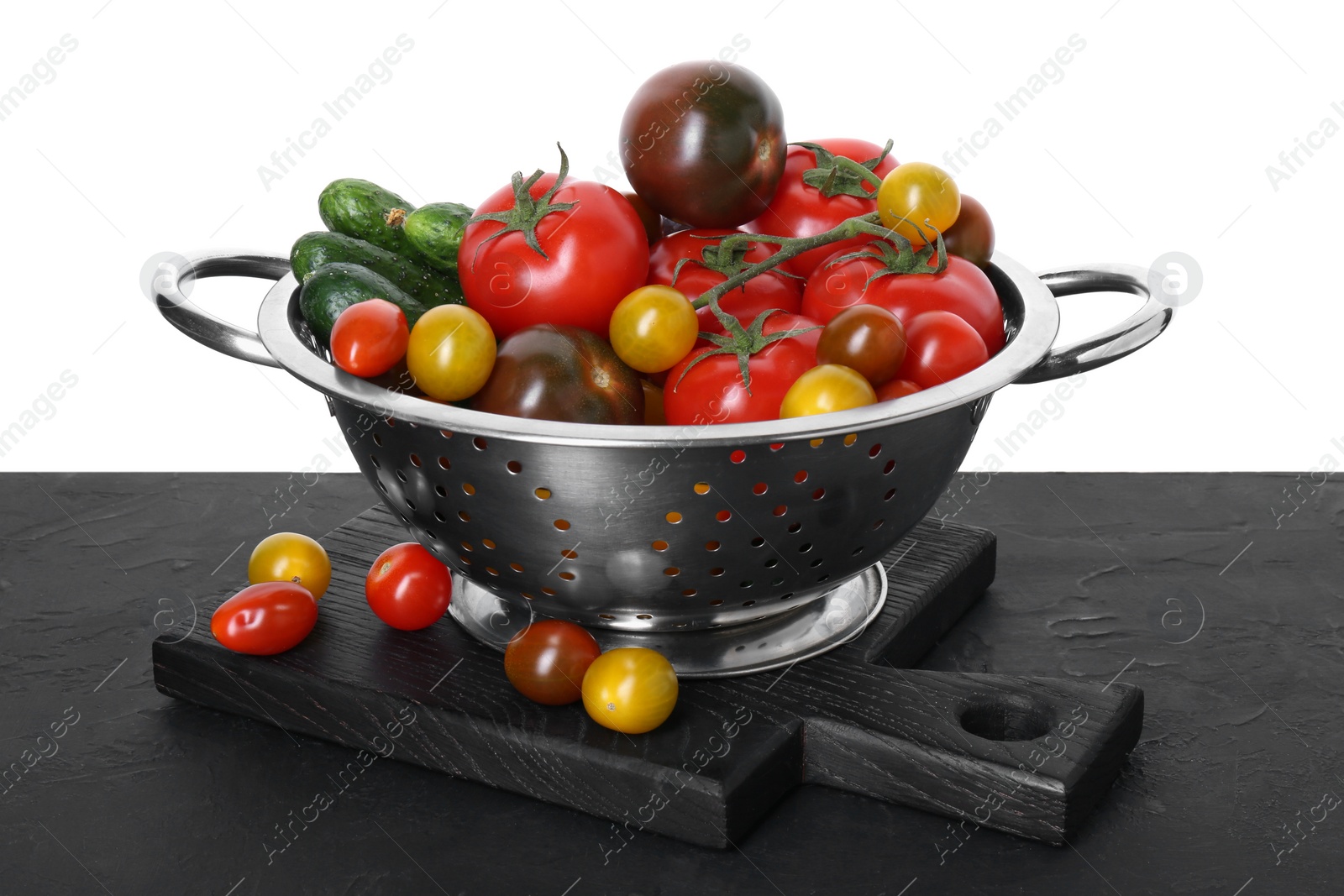 Photo of Metal colander with fresh tomatoes on black textured table against white background