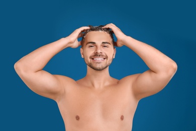 Young man washing hair on blue background