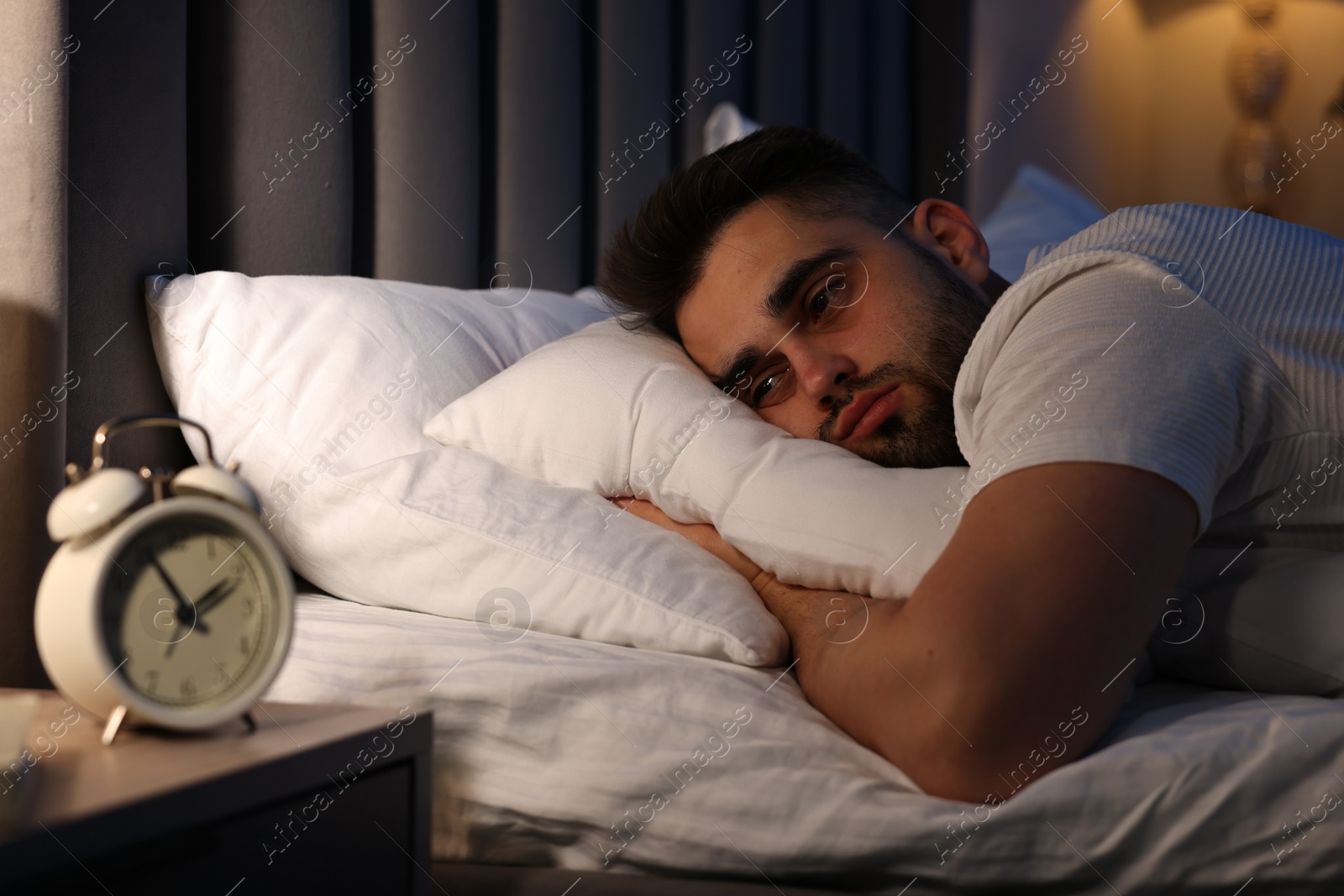 Photo of Frustrated man suffering from insomnia on bed