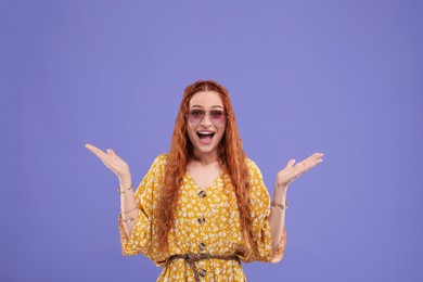 Photo of Stylish young hippie woman in sunglasses on violet background