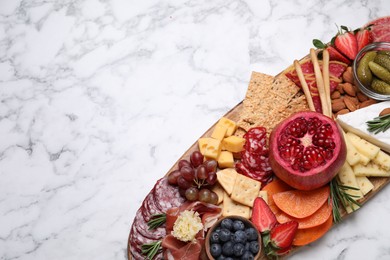 Photo of Wooden plate with different delicious snacks on white marble table, top view. Space for text