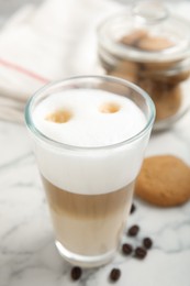 Photo of Delicious latte macchiato, cookies and coffee beans on white marble table