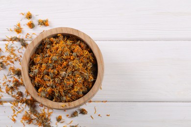 Bowl with dry calendula flowers on white wooden table, flat lay. Space for text