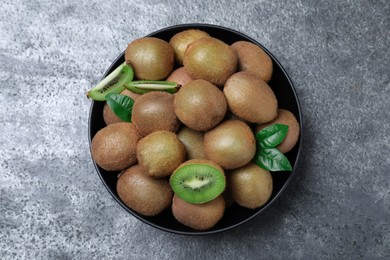 Photo of Fresh ripe kiwis in bowl on grey table, top view
