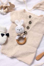 Different baby accessories on white fabric, above view