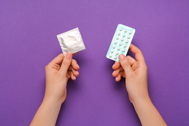 Photo of Woman with condom and contraceptive pills a on violet background, top view. Choosing birth control method