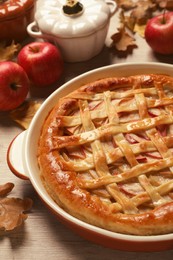 Photo of Delicious homemade apple pie and autumn leaves on wooden table. Thanksgiving Day celebration